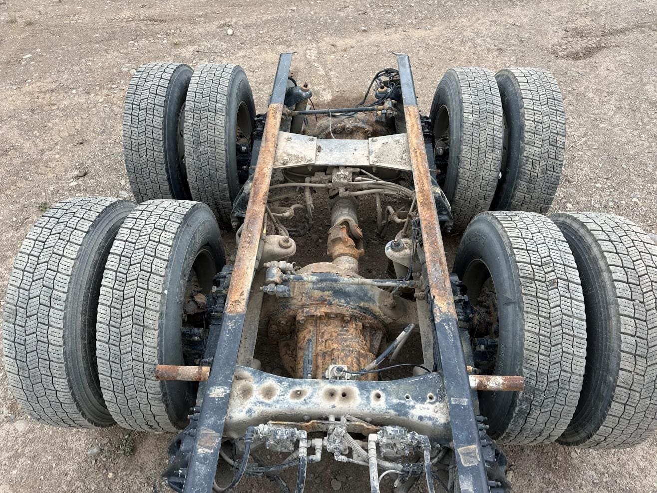 A truck frame with four tires on it.