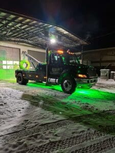 A tow truck parked in the snow at night.