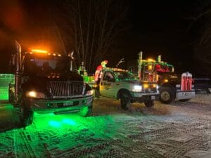 A tow truck is parked in the snow at night.