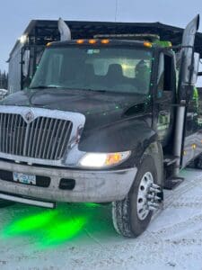 A black truck with green lights on the front.