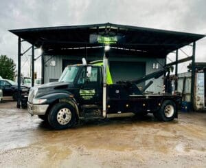 A black tow truck parked in front of a building.